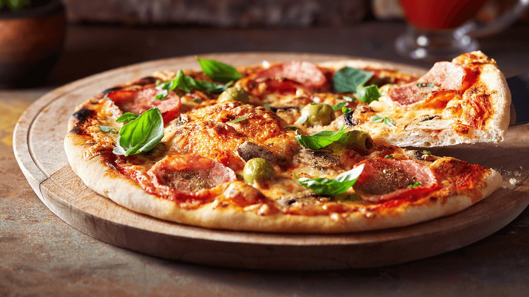 Pizza mit Salami, Pilzen, Oliven und Basilikum